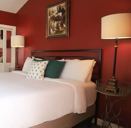 Hotel room with red walls, bed, and a lamp beside the bed at Hartstone Inn.