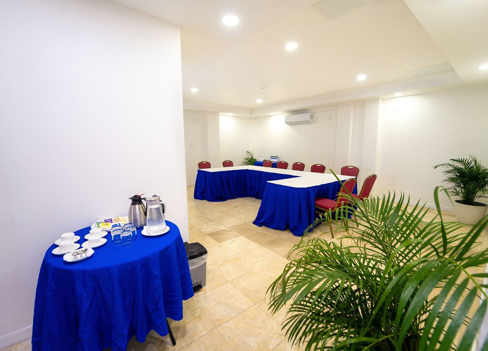 A cosy conference room setup with deep blue tablecloths and lush plants - Hotel 39, Jamaica (Montego Bay)