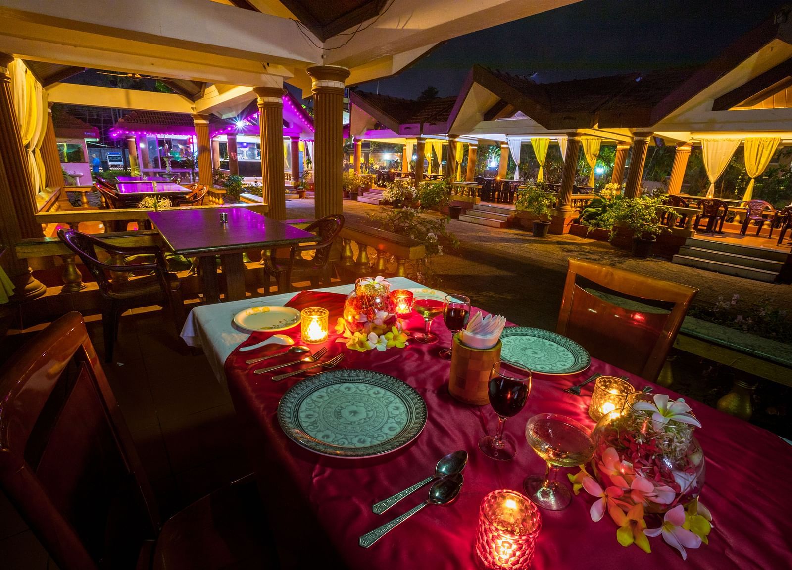 A candle light dining arrangement at Paradise Isle Beach Resort, Udupi with the cottages in the backdrop