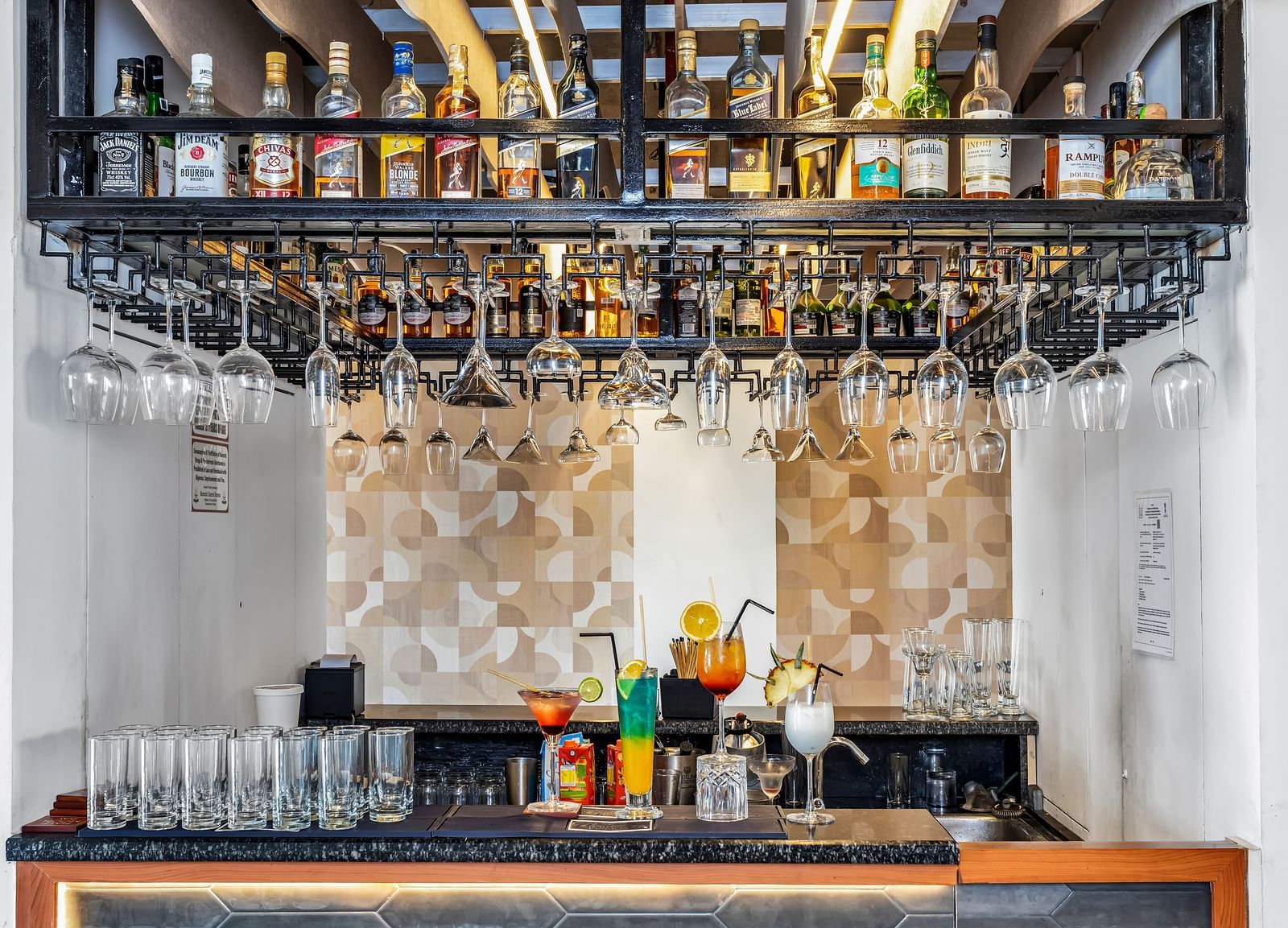 A well-stocked bar with various liquor bottles on shelves and wine glasses hanging upside down | The Citi Residenci Hotel Banskopa