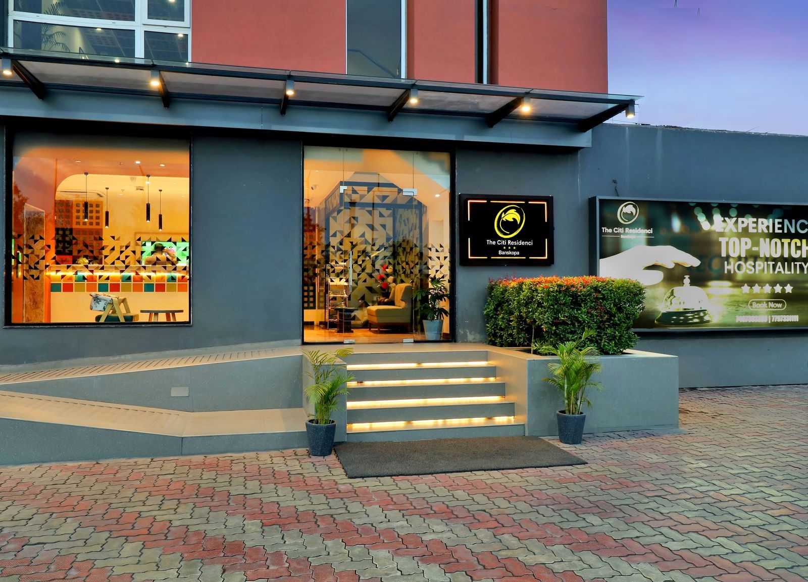 The illuminated entrance of a modern establishment with display windows and signage | The Citi Residenci Hotel Banskopa