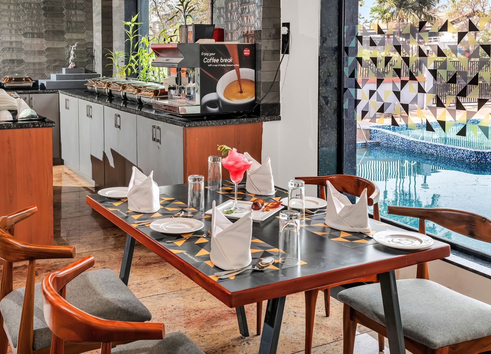 A restaurant dining area with set tables and chairs, overlooking a swimming pool through a glass wall  | The Citi Residenci Hotel Banskopa