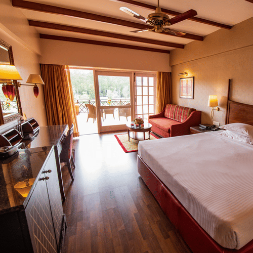 An image of a bedroom featuring a double size bed, a sofa , work desk and chair, and a cabinet table  at The Carlton, Kodaikanal