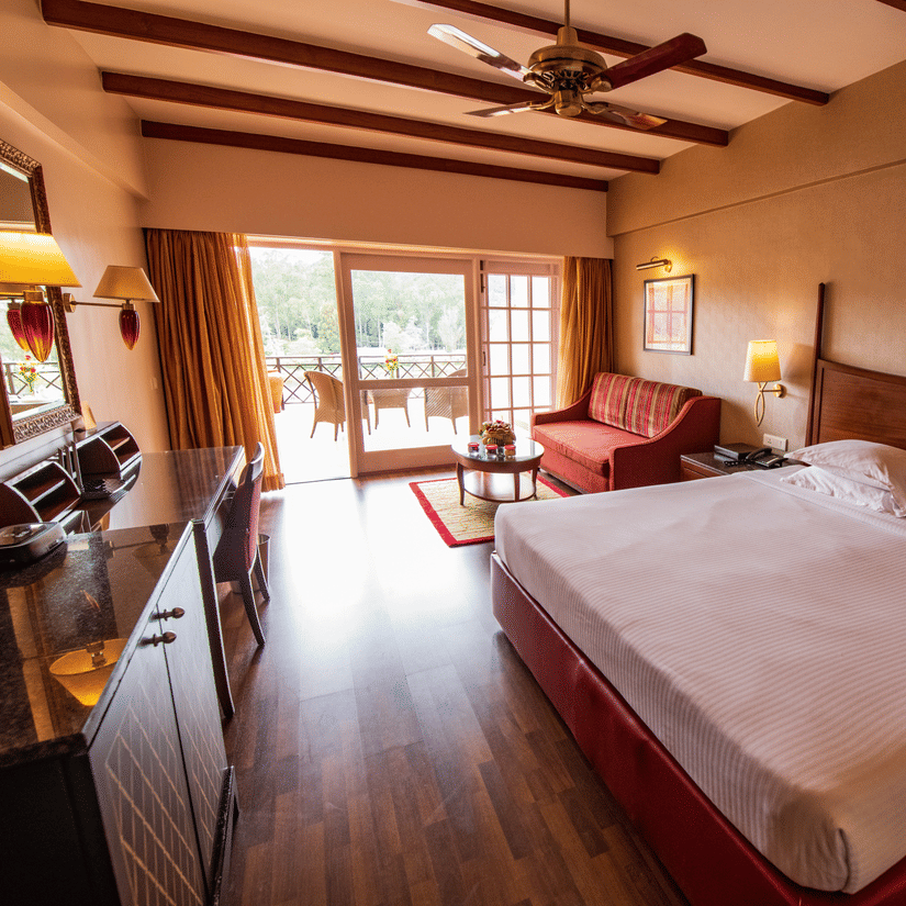 An image of a bedroom featuring a double size bed, a sofa , work desk and chair, and a cabinet table  at The Carlton, Kodaikanal