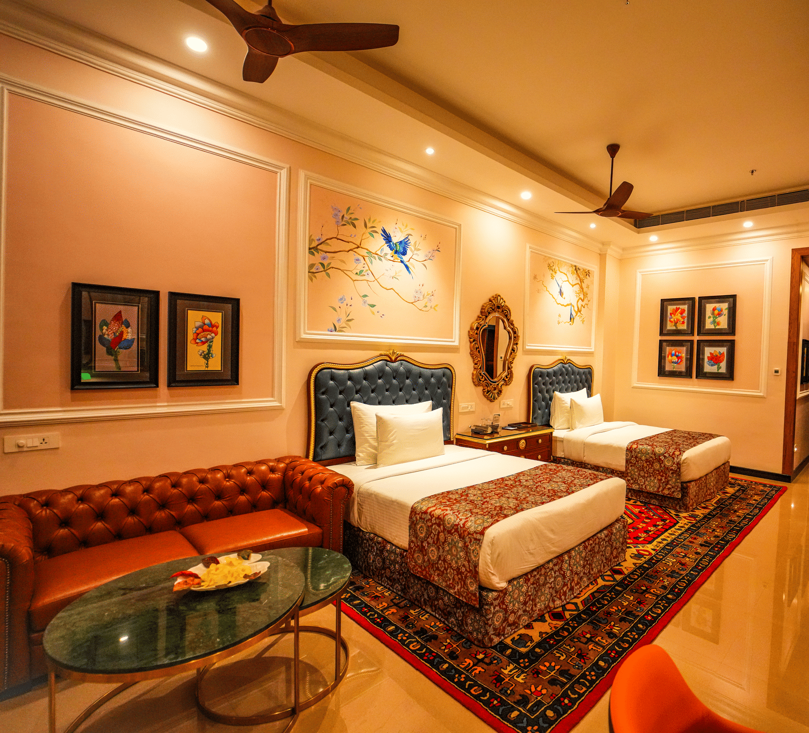 Executive Room at MAYFAIR Oasis Resort featuring twin beds, plush red sofa, and elegant interior decor.