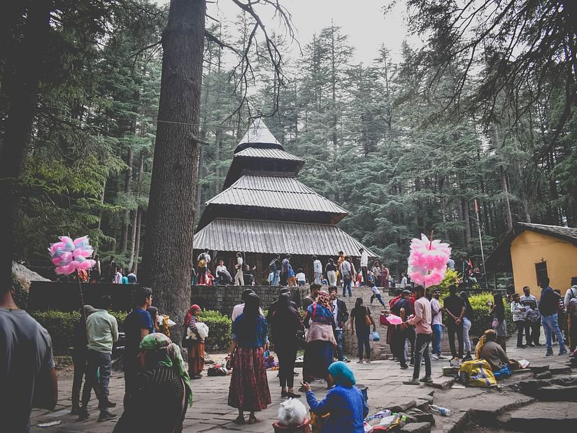 An image of people standing outside a temple with lush greenery around
