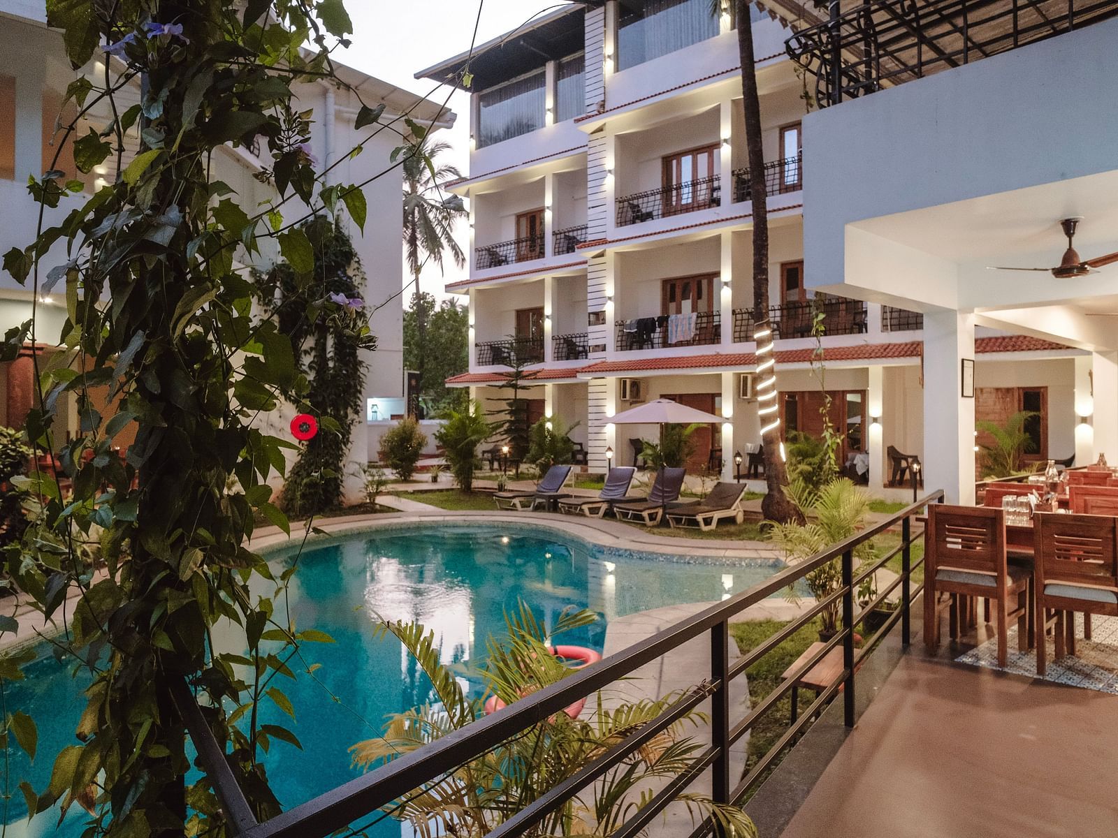 Poolside view with dining arrangements and rooms with balconies in the background at The Verda de Miranda Resort.