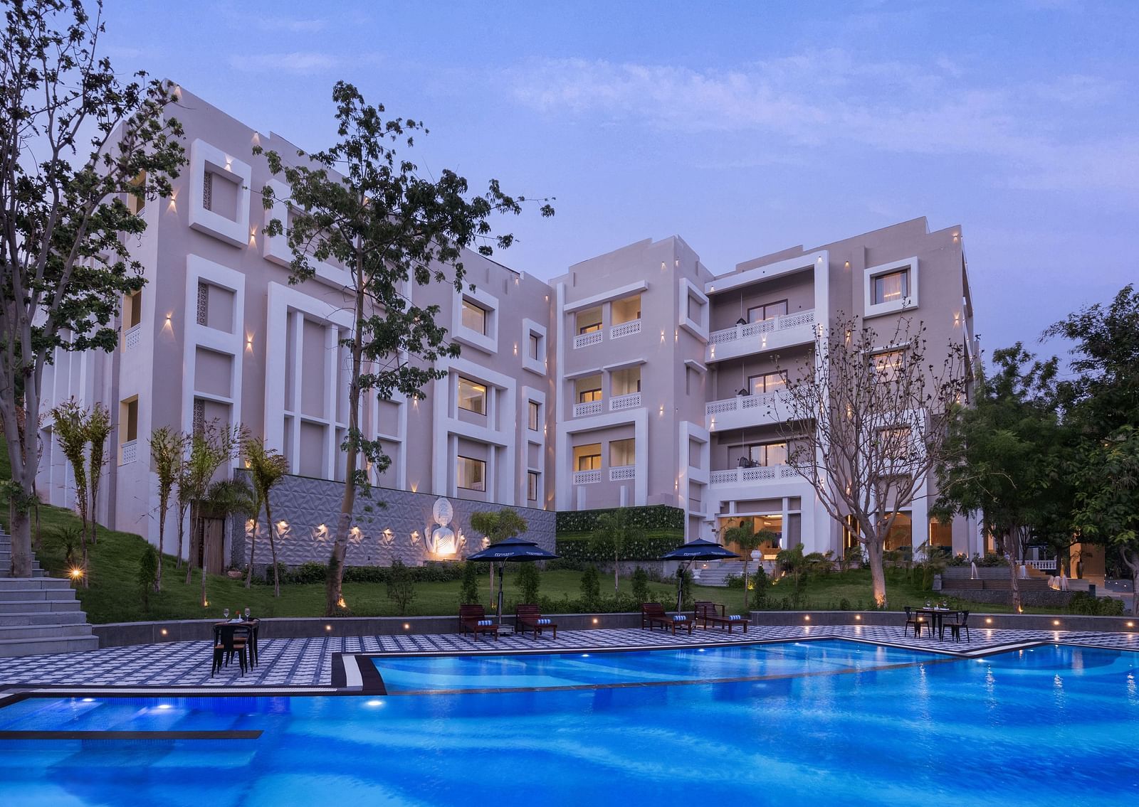 An overview of the Swimming pool with the facade of Essentia Luxury Resort & Spa, Udaipur in view.