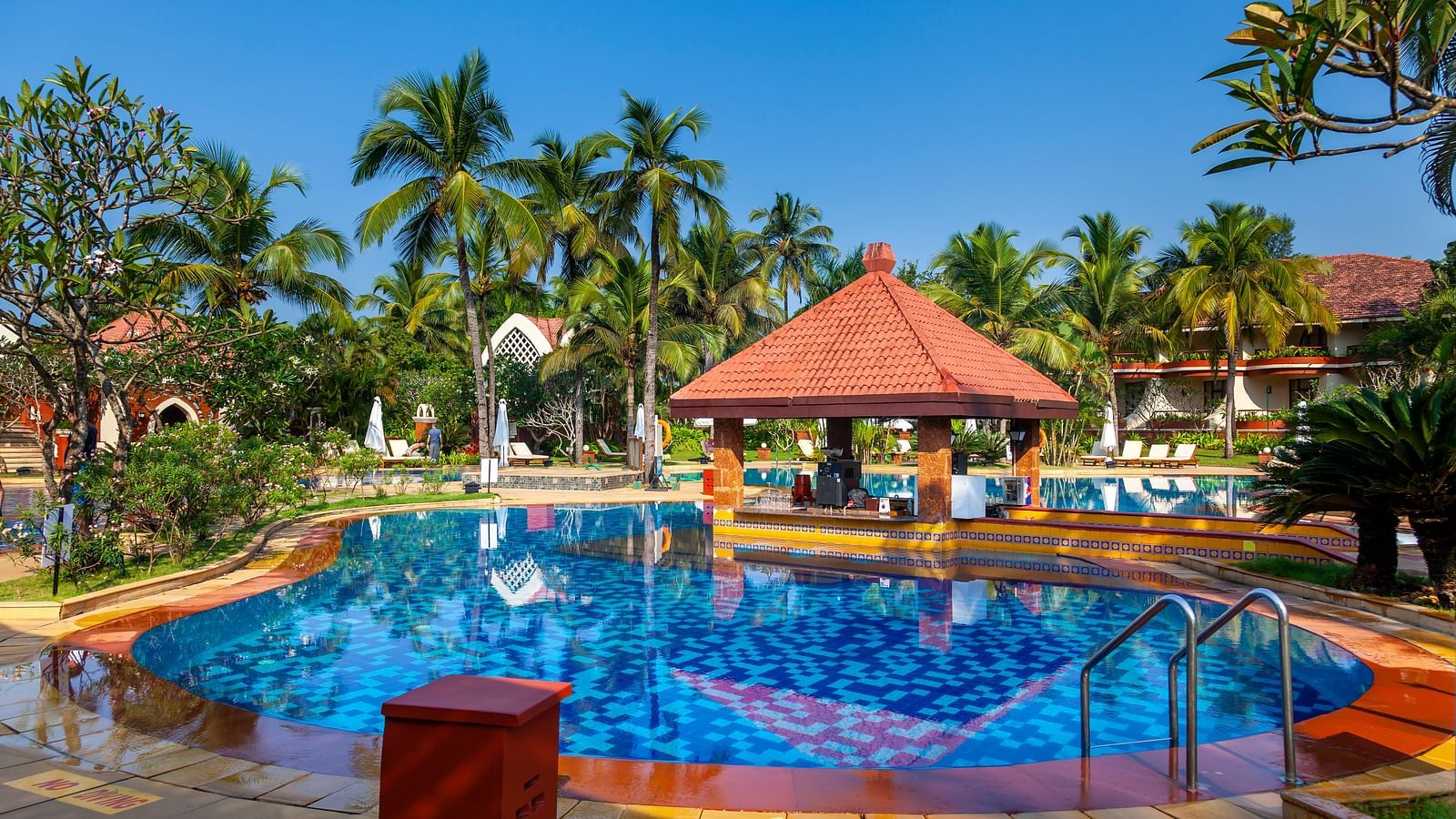overview of the swimming pool with trees in the background - Caravela Beach Resort Goa