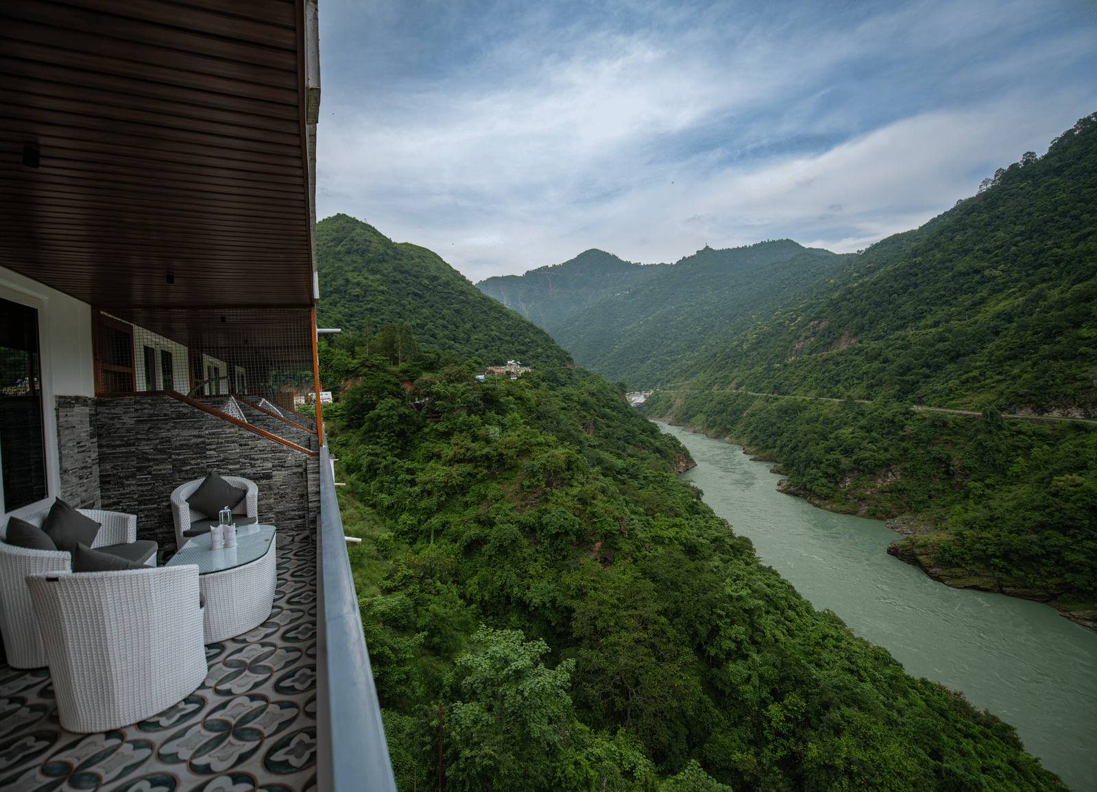 A balcony in the executive room at The Tattva Devaprayag with a view of the mountains and the river.