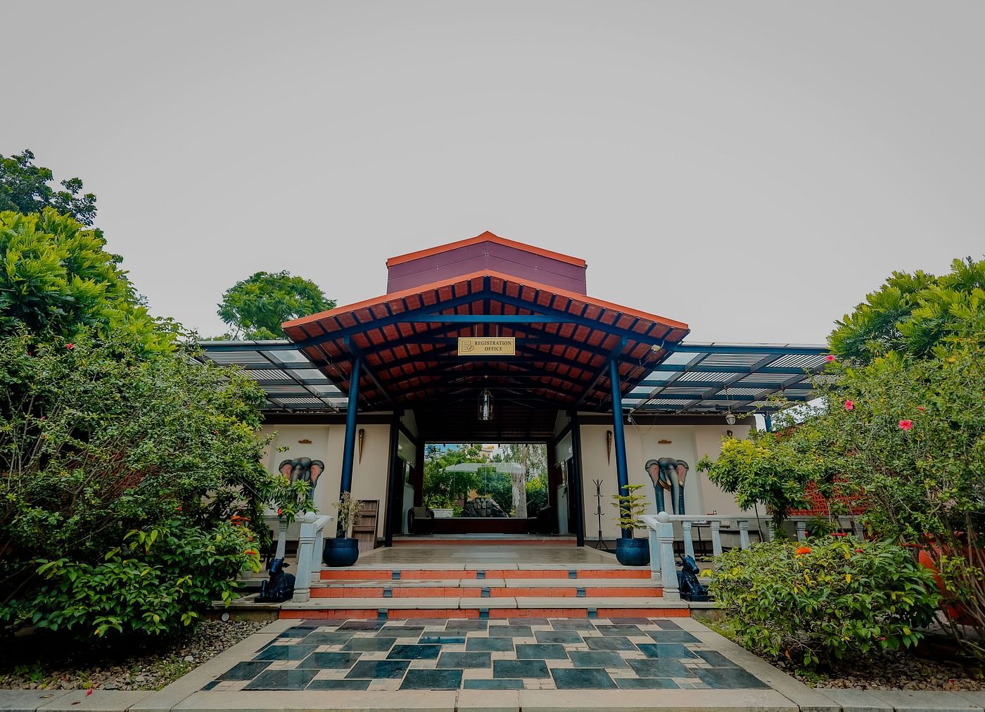 The entrance to a building with a tiled roof and steps leading up, possibly at Nirantara Resort & Spa in Bengaluru.