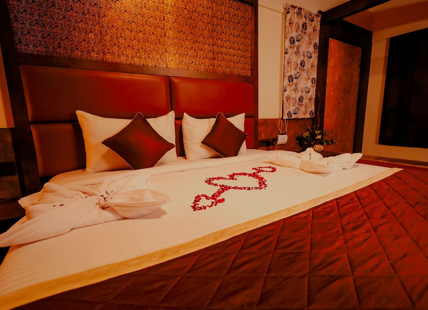 A neatly made bed with decorative towels and flowers in a room at Nirantara Resort & Spa