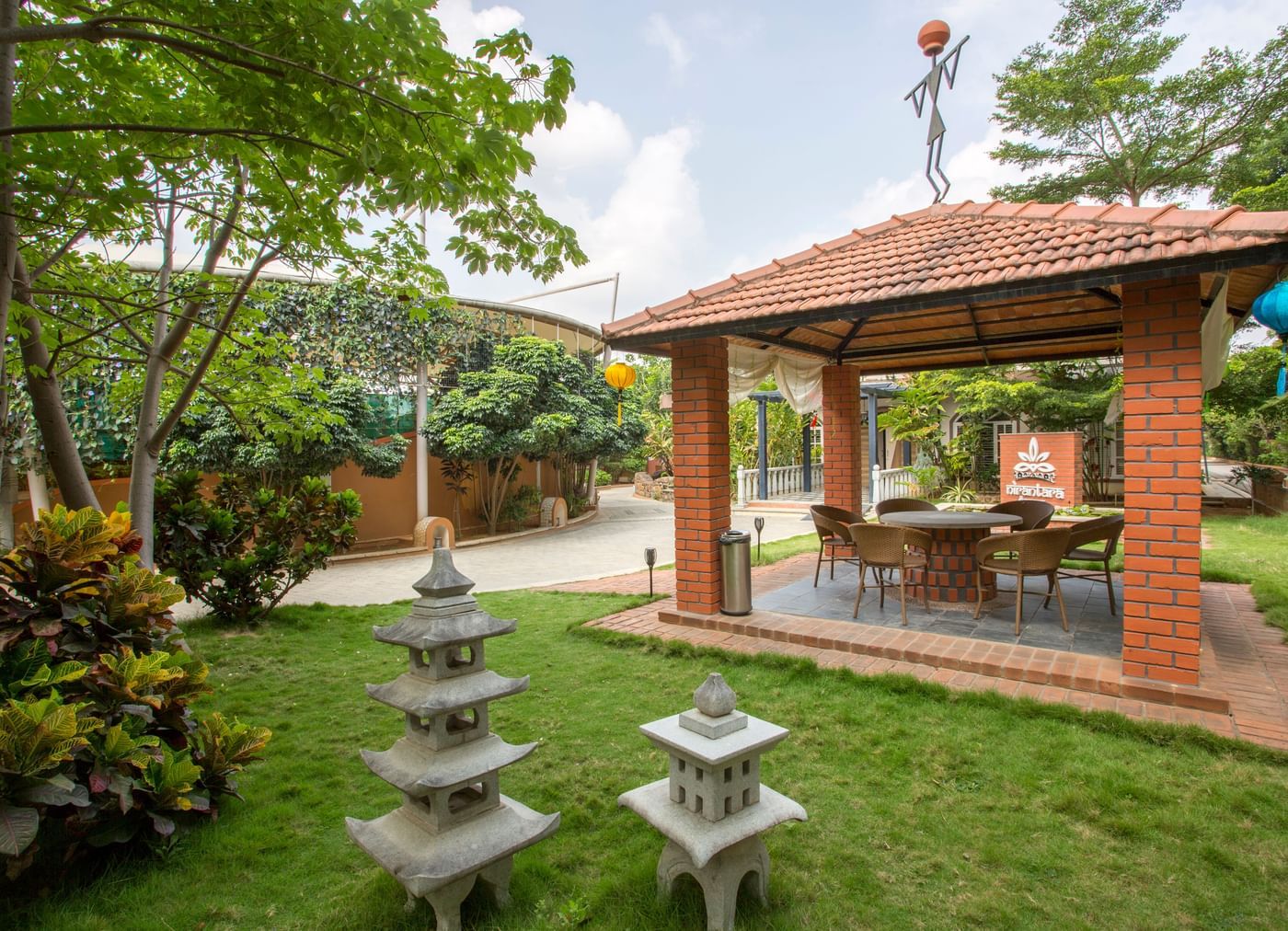 Garden area with traditional stone sculptures and greenery at Nirantara Resort.