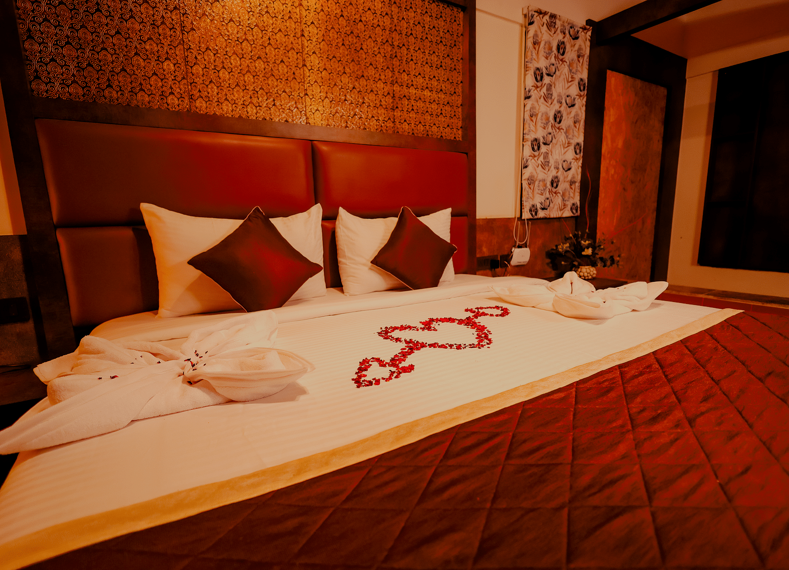 A neatly made bed with decorative towels and flowers in a room at Nirantara Resort & Spa
