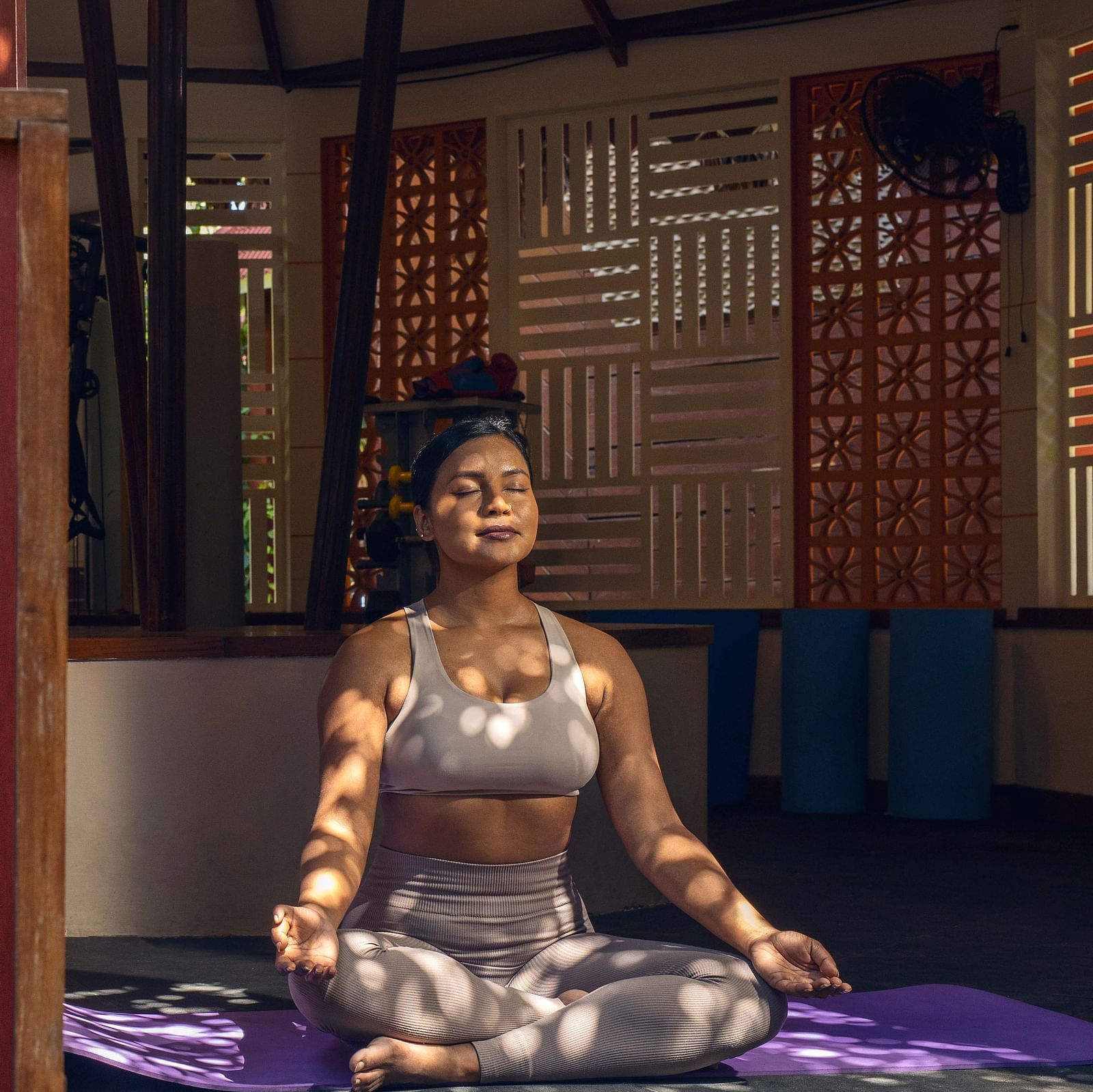 : A sign for the  Opal Fitness Center displayed alongside a statue of a person in a meditative pose. The background includes rustic wooden elements and a calm environment - Coral Reef Resort & Spa, Havelock