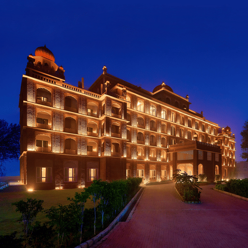 An evening view of our hotel in Amritsar illuminated warm yellow lights and dark blue sky in the background - Sarovar Premiere Amritsar