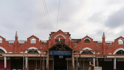 New Market in Kolkata with a person walking in front of it and numerous other people sleeping in front of it