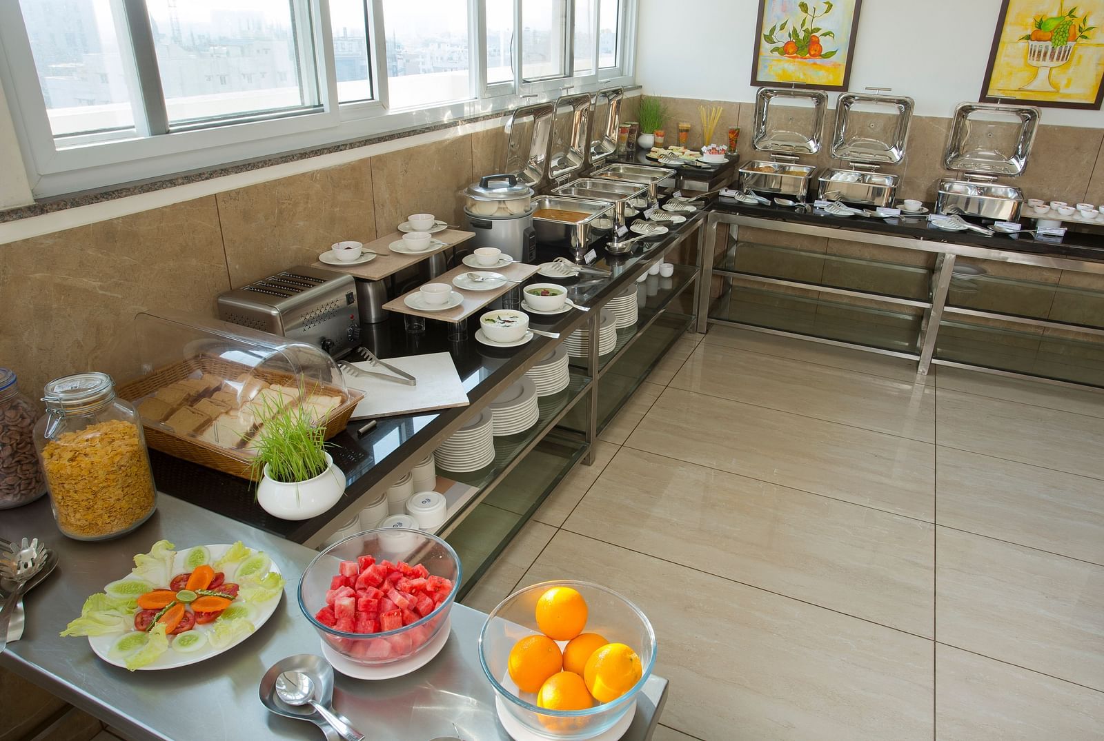 A hotel breakfast buffet with a variety of food items on display near a window with a city view - De Venetian by TGI, Brookefield