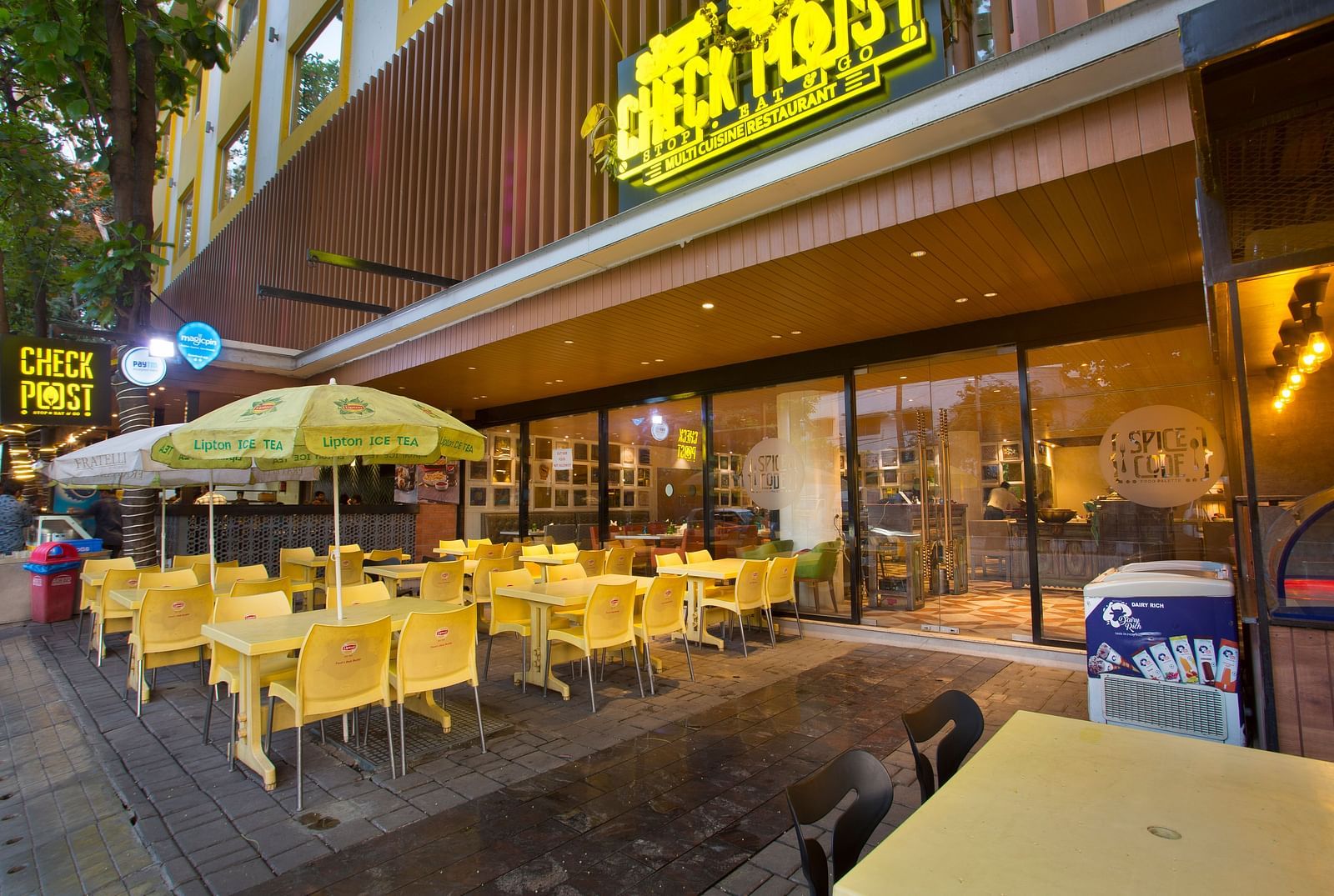 an outdoor restaurant with umbrellas mounted on the tables to provide shade - Hotel Fountain Tree By TGI - JP Nagar, Bangalore
