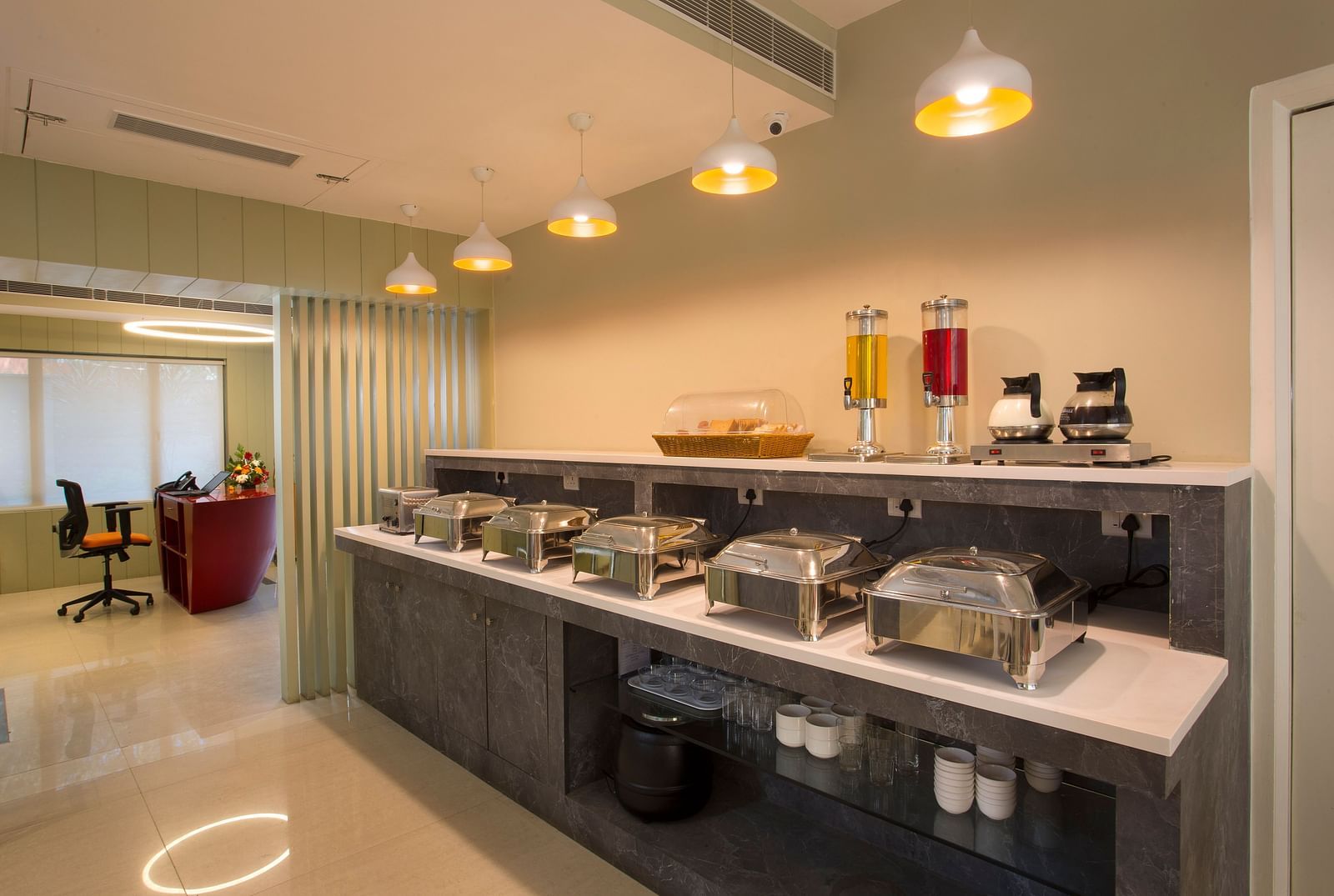 A bright restaurant buffet area with food warmers, juice dispensers and a reception desk in the background - Hotel Langford Keys by TGI, Shanti Nagar