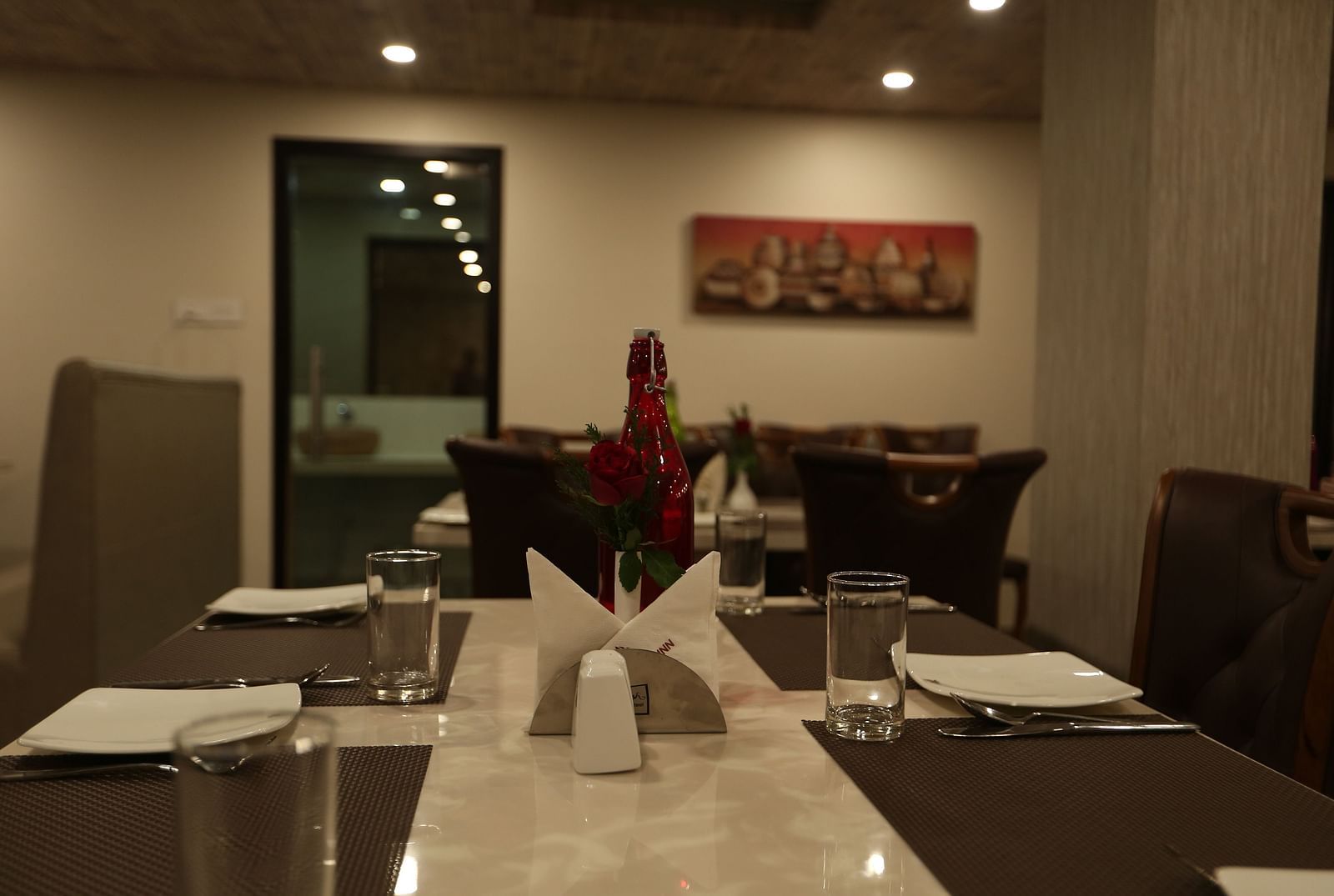 A well-lit restaurant area with dark wood furniture and table settings  - TGI SPS Grand, Coimbatore
