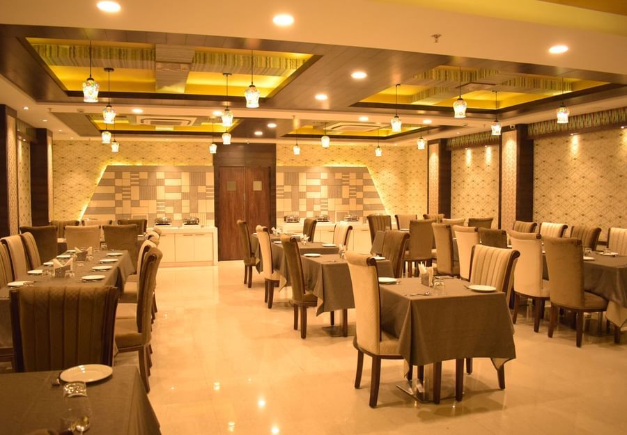 A modern and elegantly designed dining area with neatly arranged tables and warm lighting, showcasing a fine restaurant in Varanasi - Hotel Uday Palace.