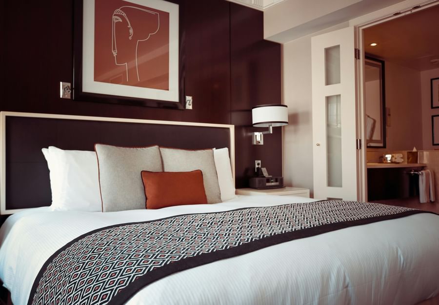 A hotel room with a double bed, soft pillows and an artistic frame.