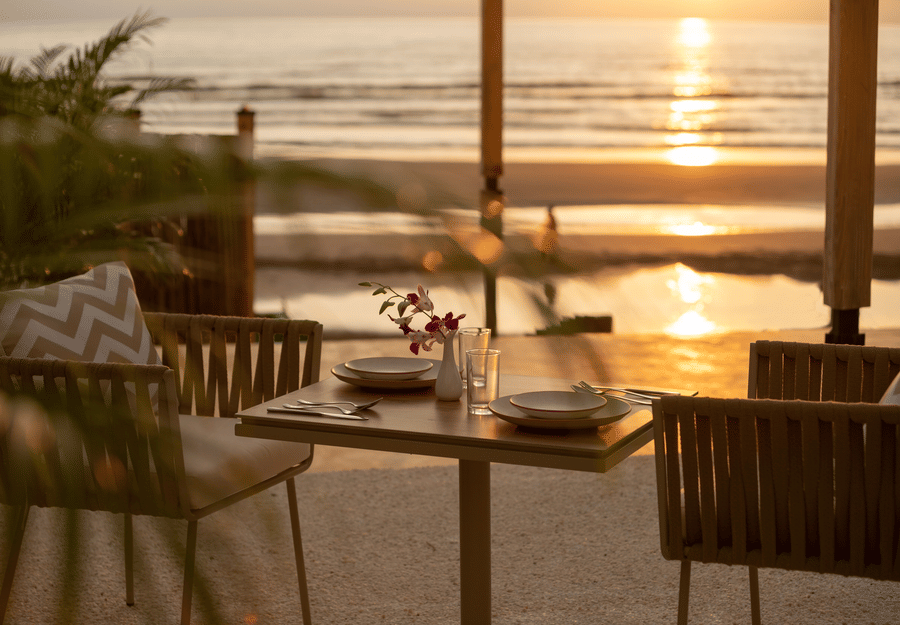 A close up shot of a table with two chairs at saz on the beach restaurant during sunset with sun rays reflecting on the sea waves in the background