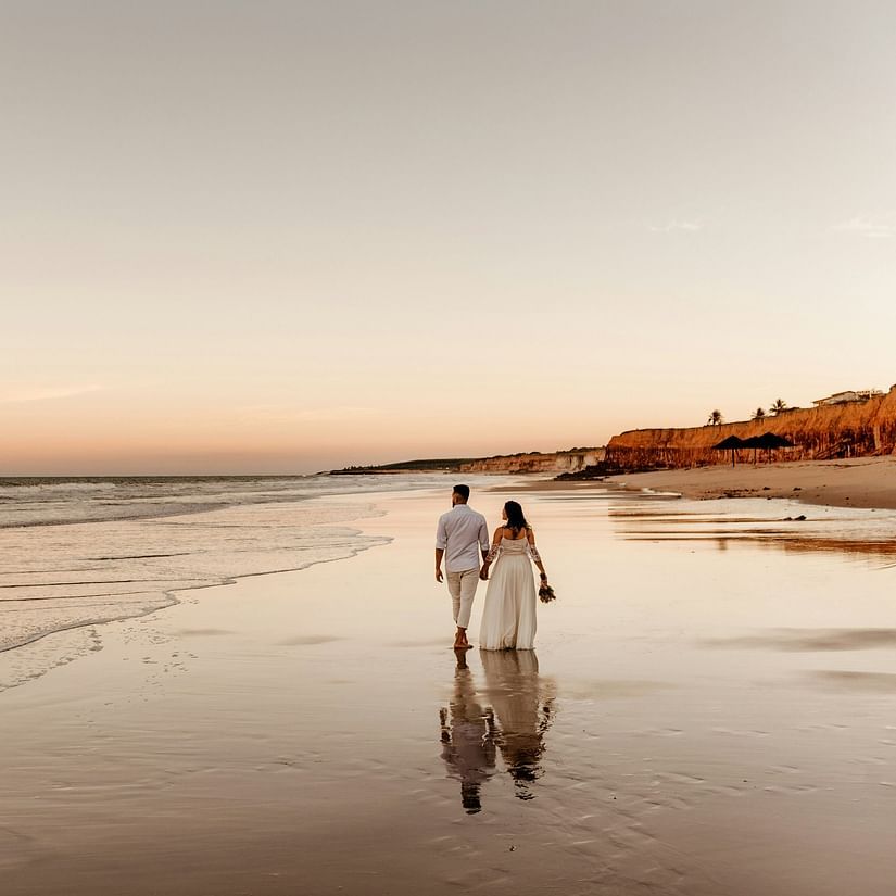 a couple walking on the beach with waves overlapping on the beach