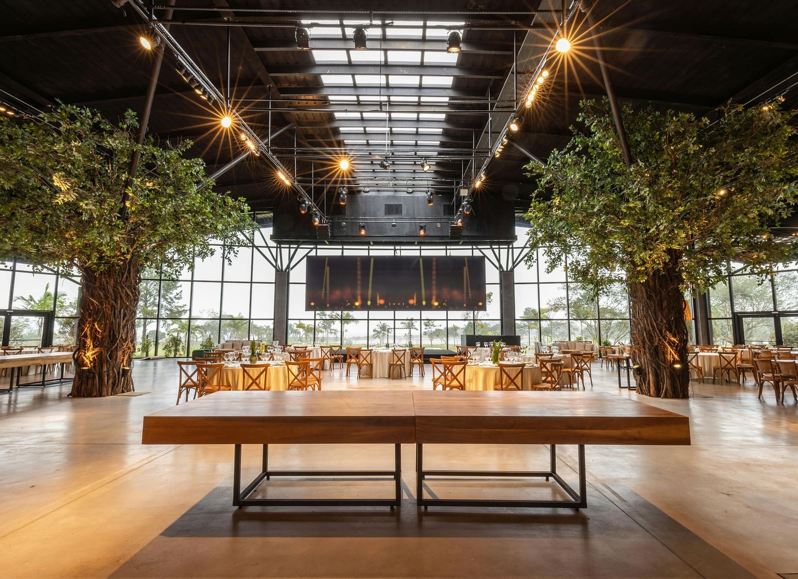 A wide angle image banquet hall with round round arrangement and a long and decorative tree  | Mango Hill, Yercaud