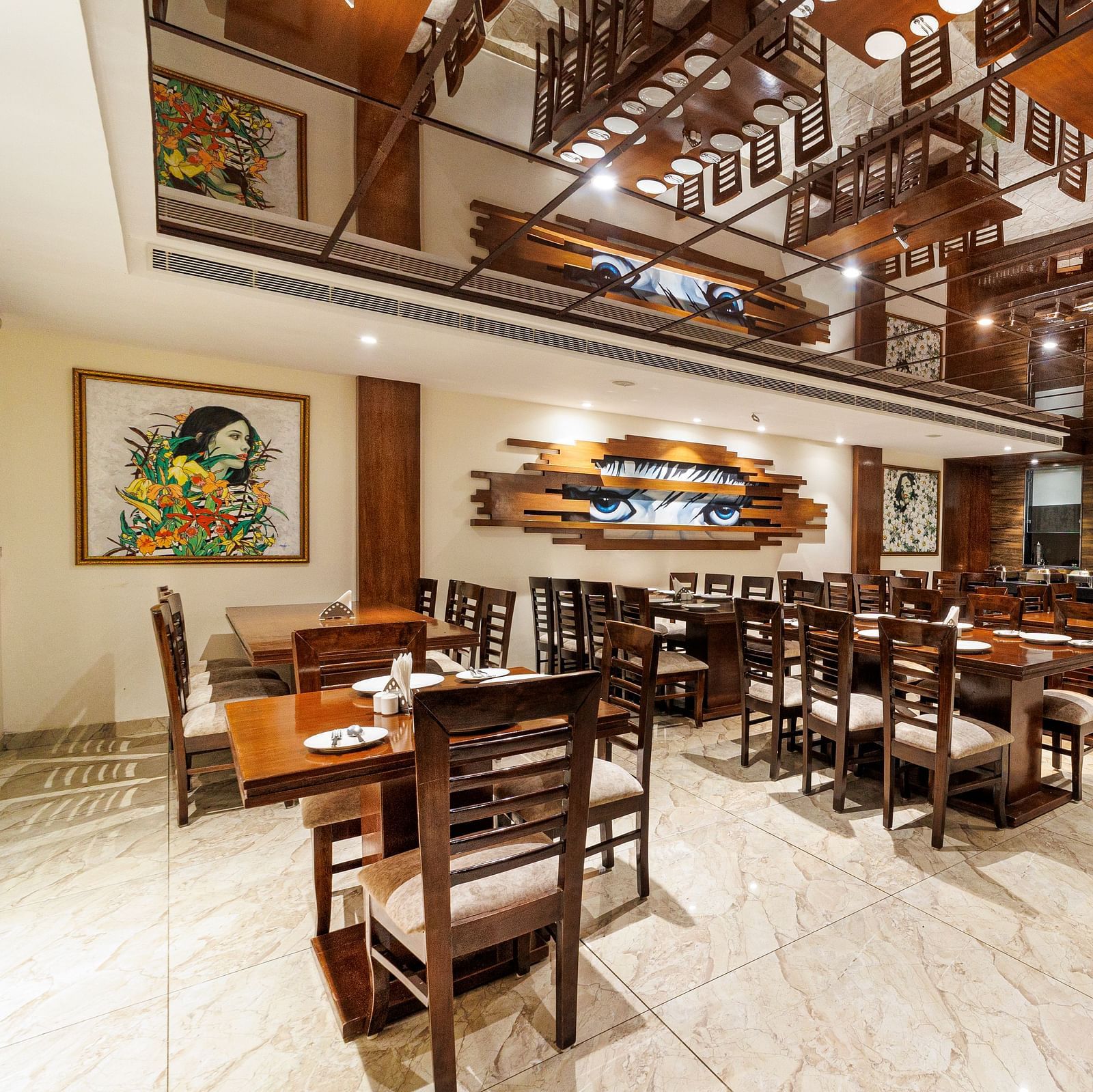 Restaurant at Inde Reva Resorts Rishhikesh featuring wooden furniture, open ceiling design, framed art, and tiled flooring.