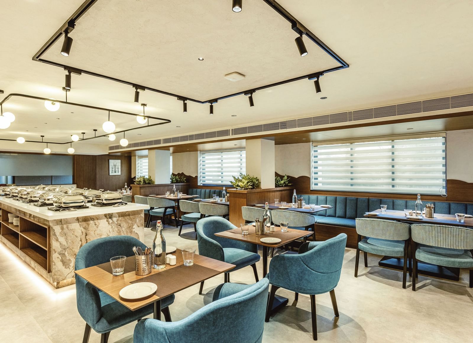 A wide shot of the restaurant at Mango Hill Central, Chennai, showing tables with blue chairs and a buffet area.