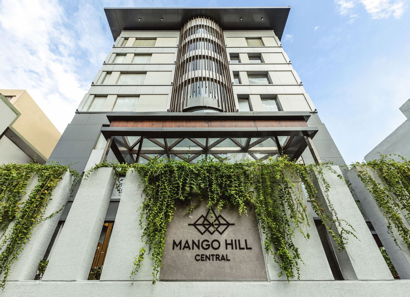 A straight-on exterior view of Mango Hill Central, Chennai, showing the multi-story building facade and the hotel name on the wall.