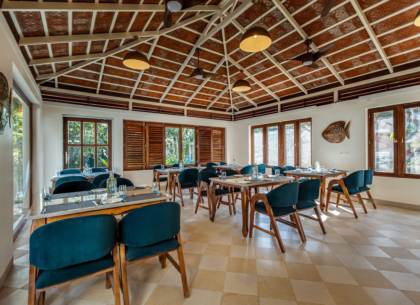Wide angle shot of restaurant dining area with wooden tables, blue chairs, and a high, patterned ceiling | Mango Hill Shallow Beach Resort ECR