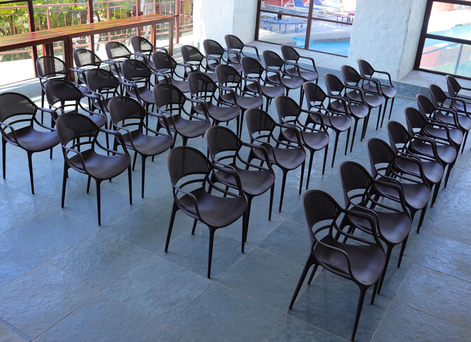 Banquet hall with rows of plastic chairs and a view of the pool.