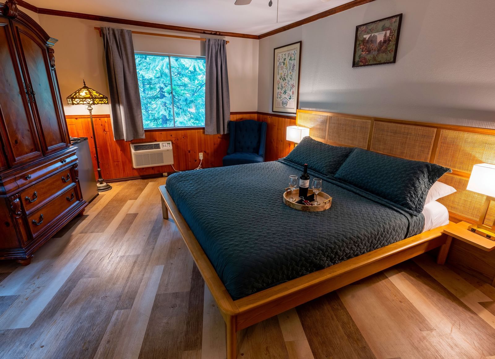 Cozy guest room at Narrow Gauge Inn featuring dark blue bedding, wooden furniture, and warm lighting.
