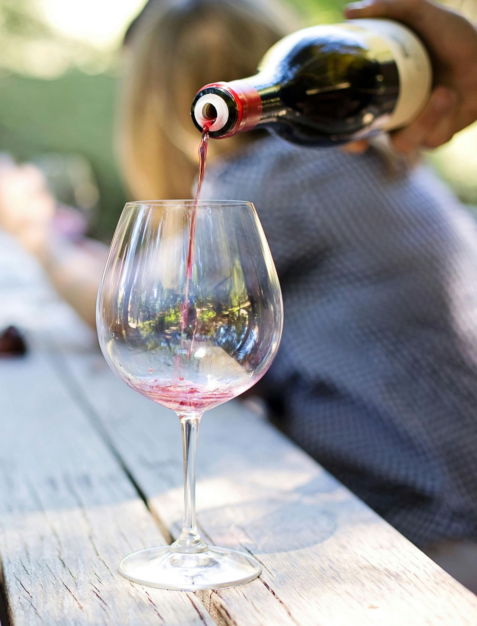 Wine being poured into a glass on a wooden table.