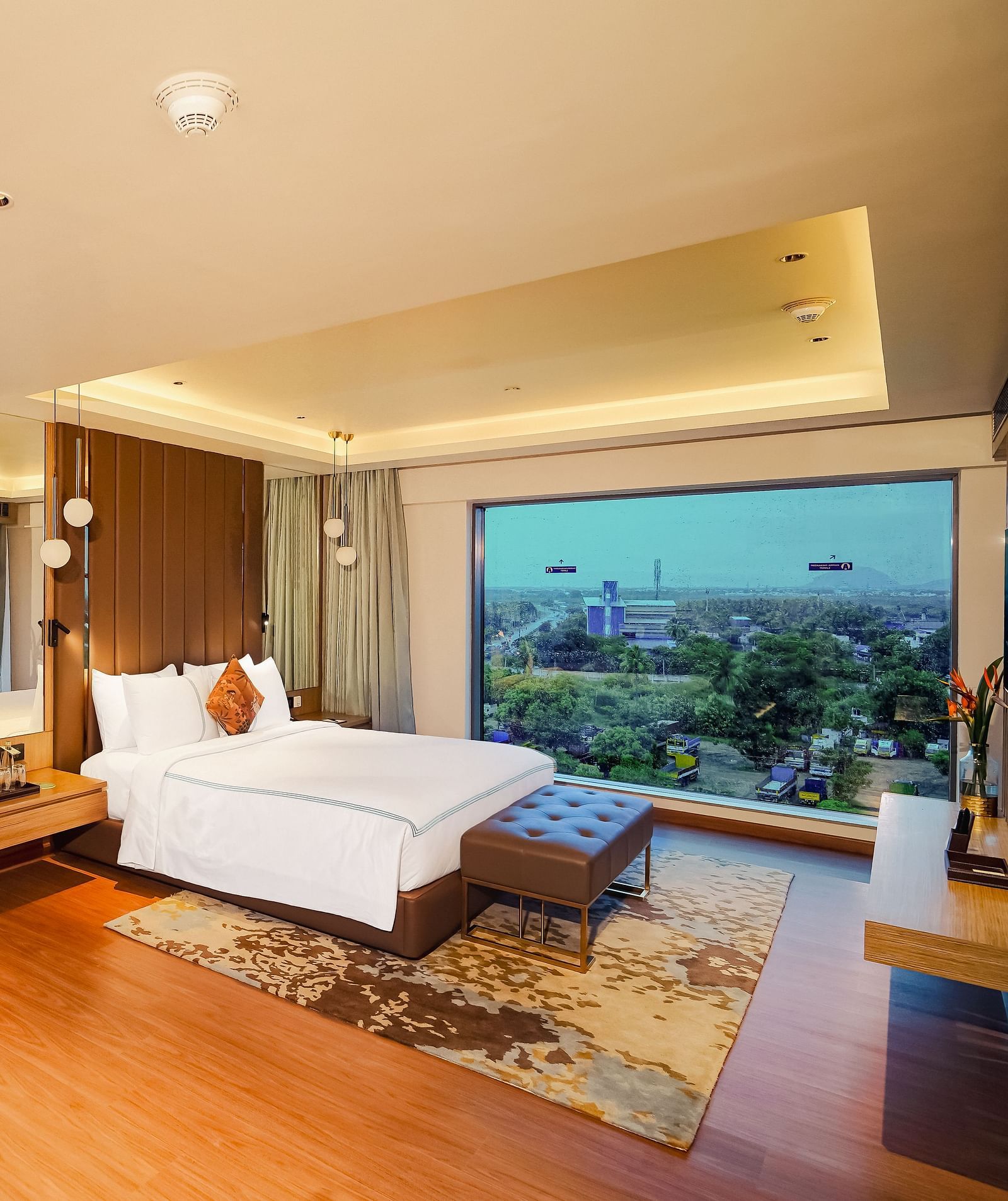 A beautiful image of a hotel room in Madurai with a large bed, a couch, and a wall-mounted television
