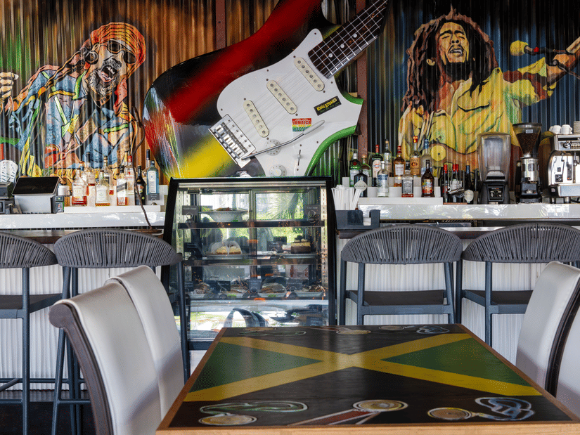 The Strings Cafe and Bar with high chairs, a counter with bottles and glassware, and a colourful mural featuring musical elements behind the counter at S Hotel Kingston.