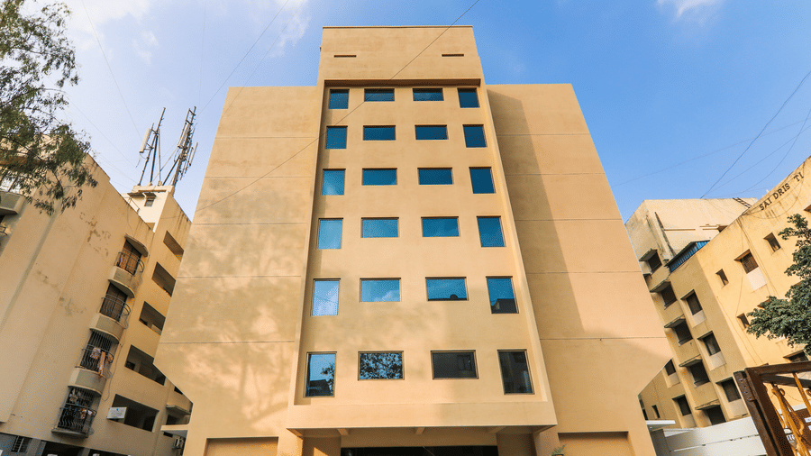 A building with multiple windows and parked cars in front along the street. | Magnus Square Exterior