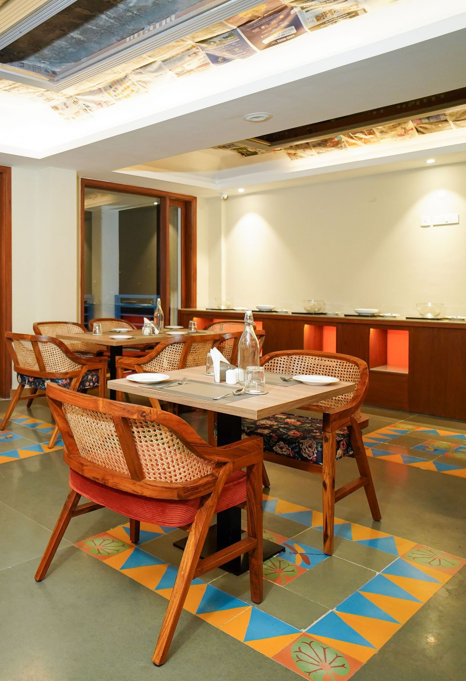 A dining area with multiple tables and chairs, featuring wooden accents and a patterned ceiling | Sukama Resort & Spa, Nainital