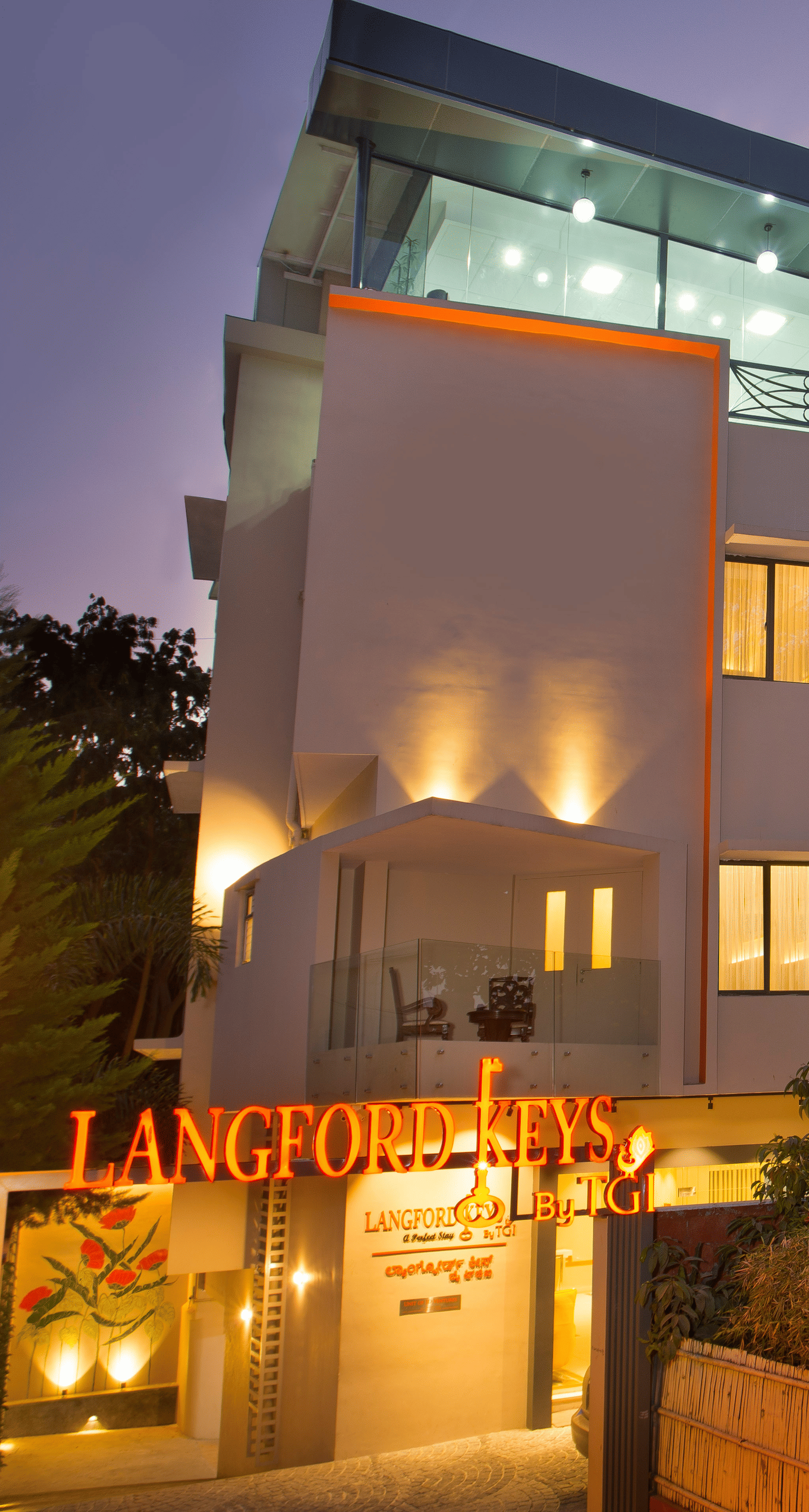 The exterior entrance of Langford Keys Hotel showing the signboard with reflective windows and modern architecture at dusk - Hotel Langford Keys by TGI, Shanti Nagar