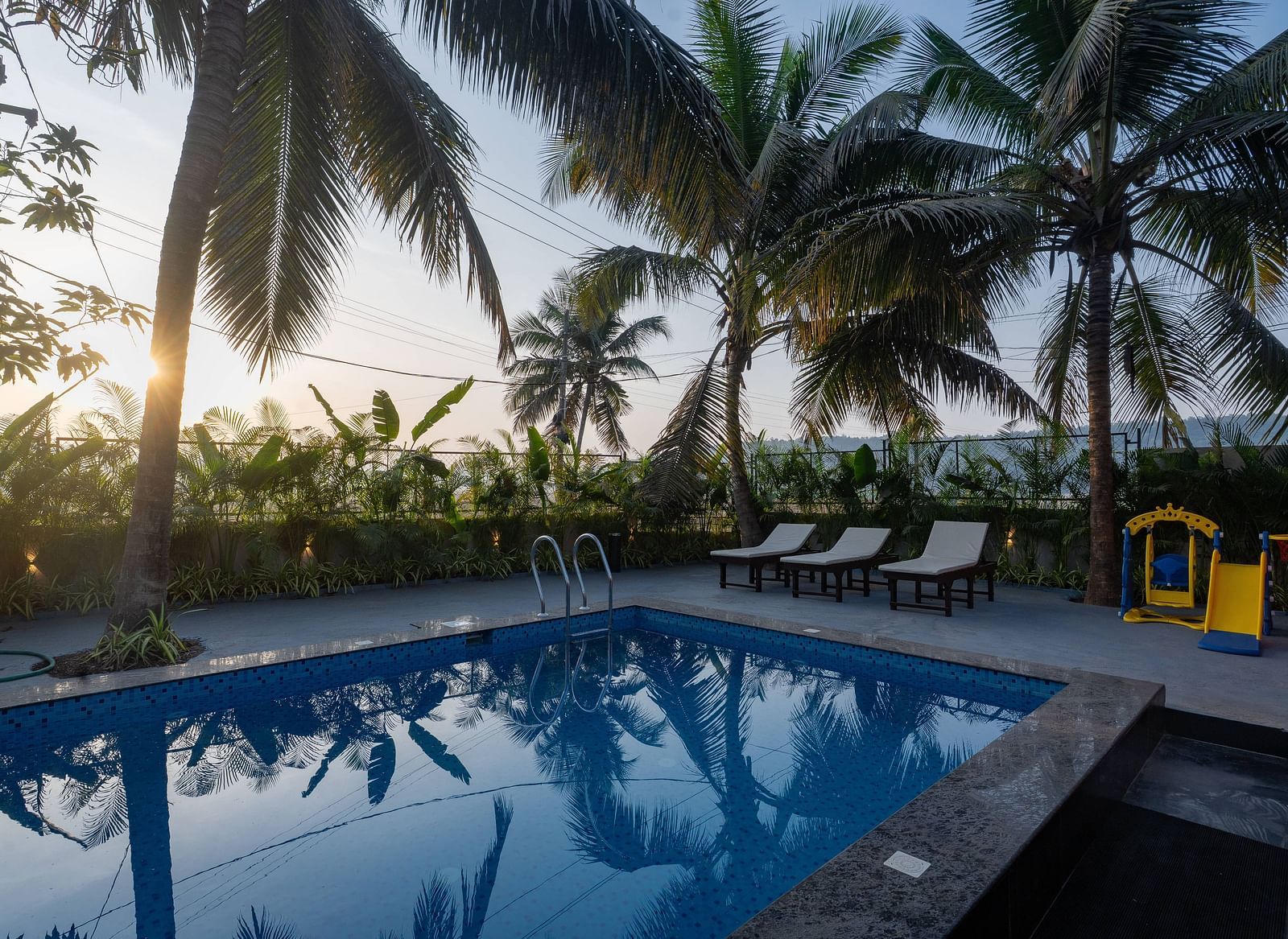 Serene outdoor swimming pool surrounded by coconut trees and tropical vibes at Kssemya.
