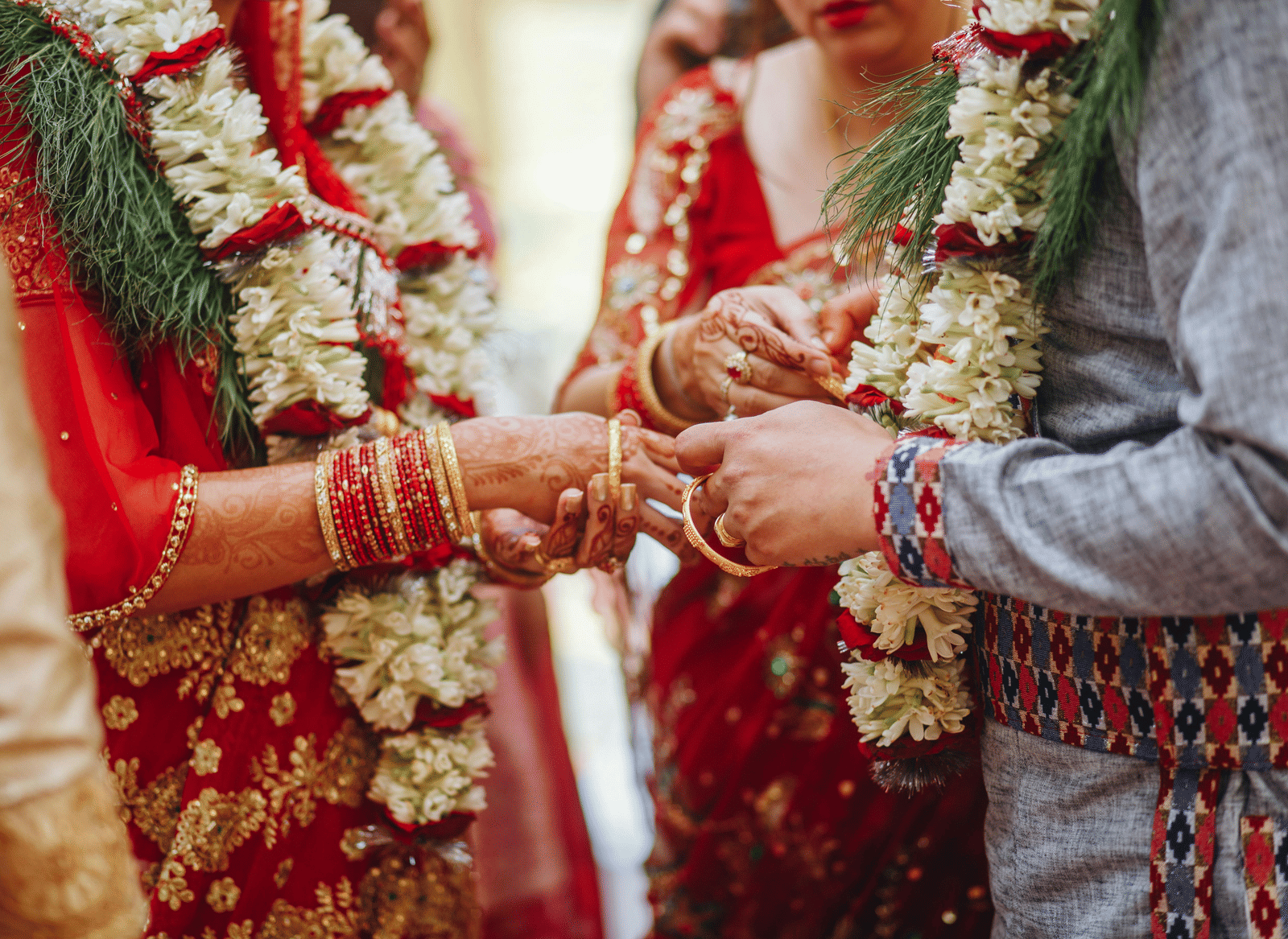 A couple wearing flower garlands exchanging rings during the wedding ceremony.