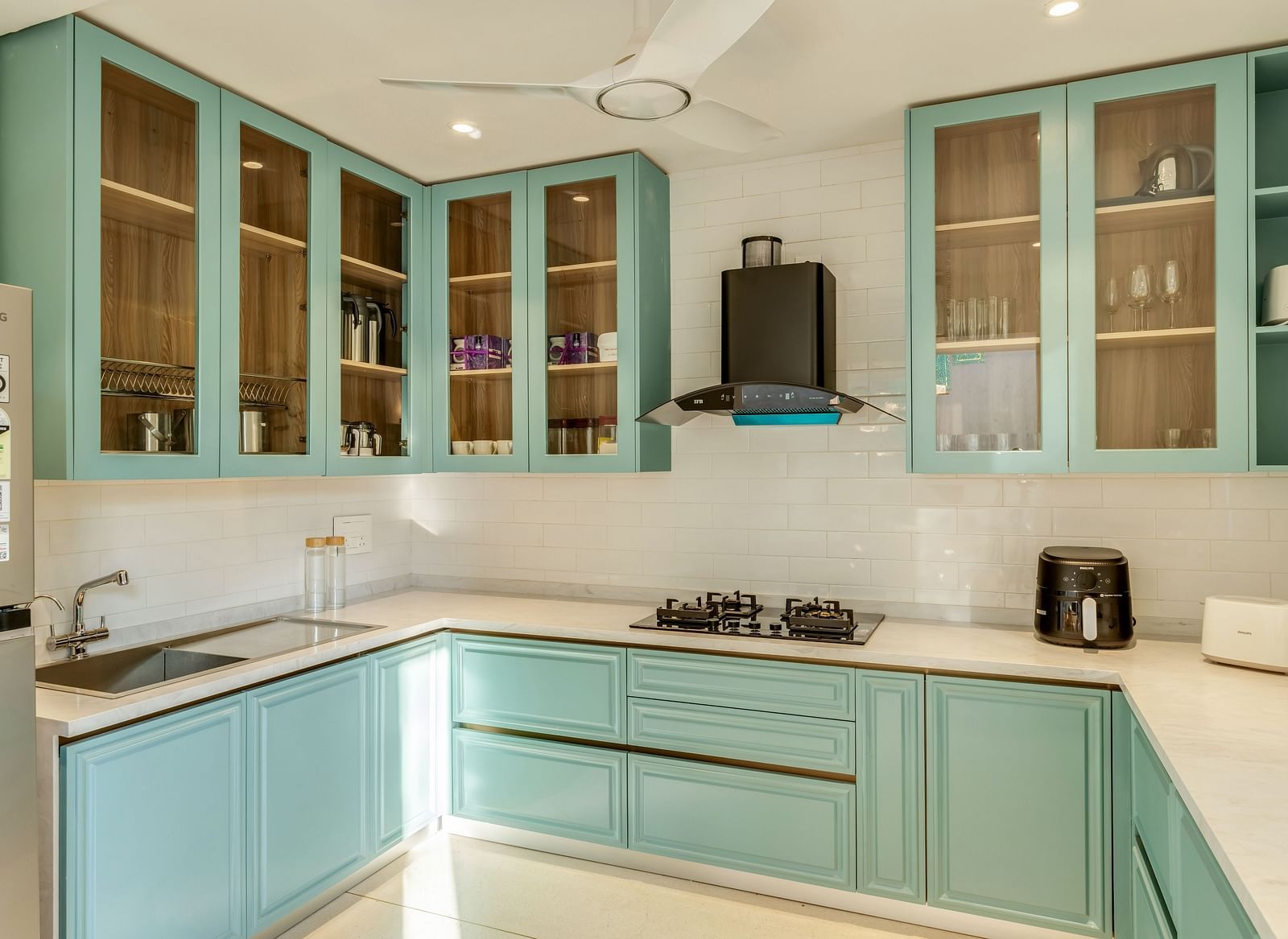 A well-equipped kitchen featuring pastel blue cabinets, glass shelving, and ample counter space, bathed in natural light - BluSalzz Villas - Alocassia, Anjuna