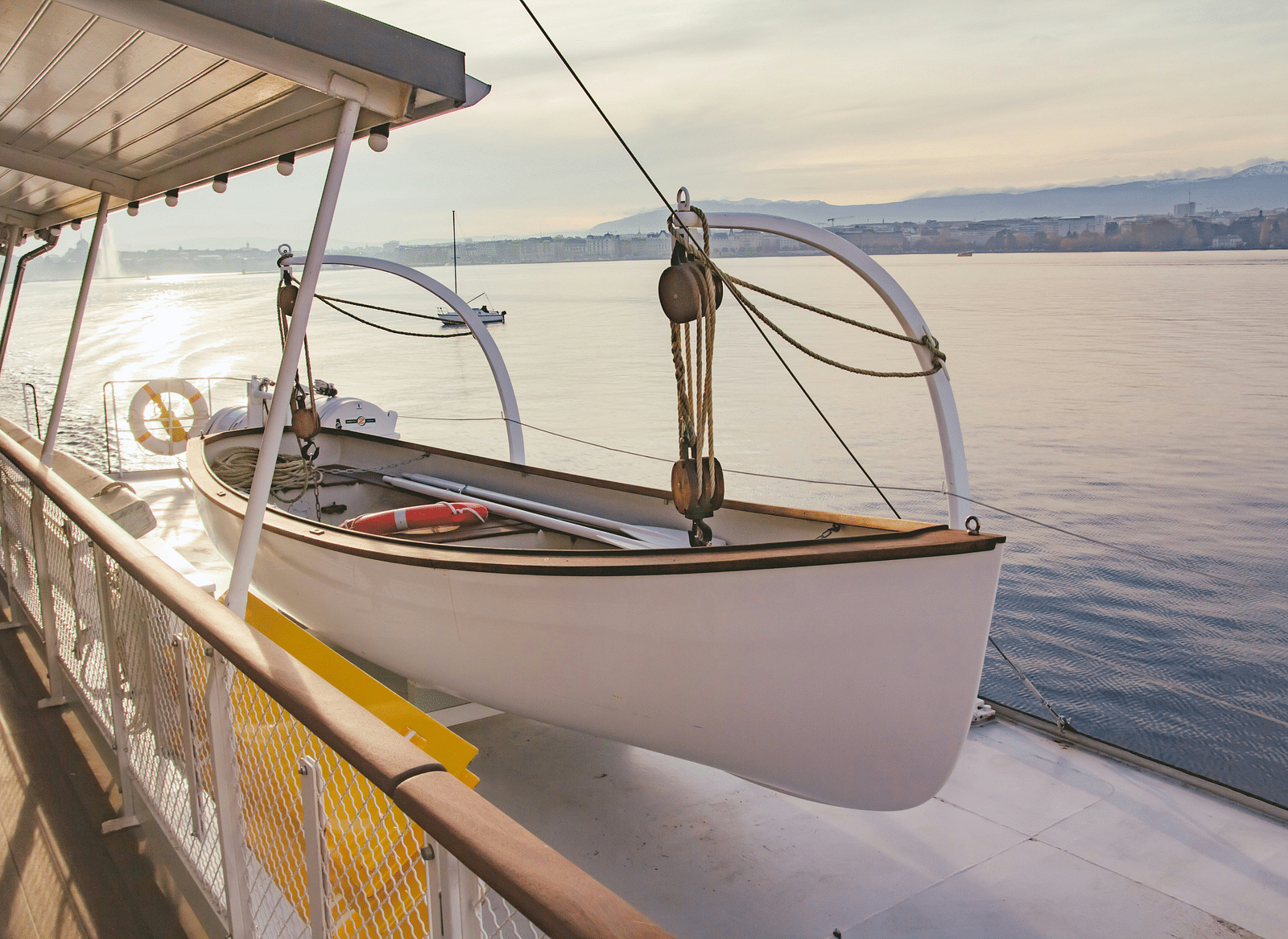 Image of a boat suspended with ropes beside a waterbody.