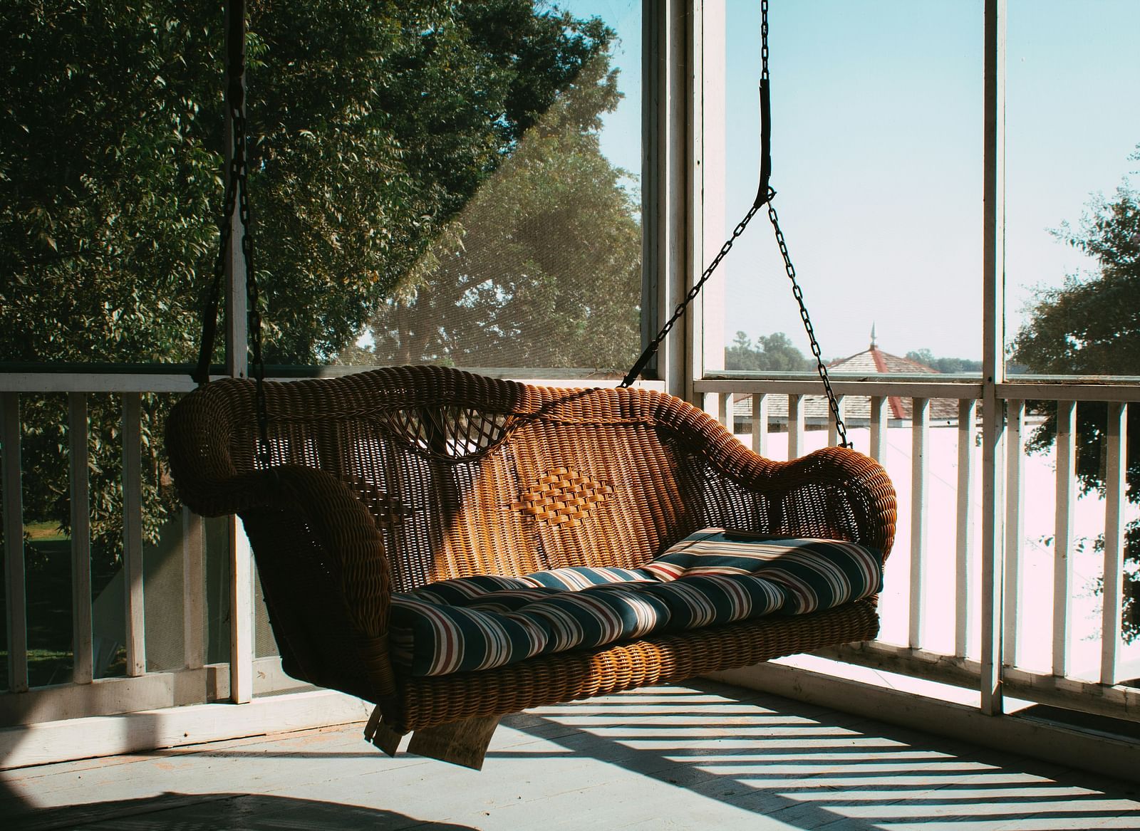 A swing with cushions placed for seating, set against a backdrop of trees