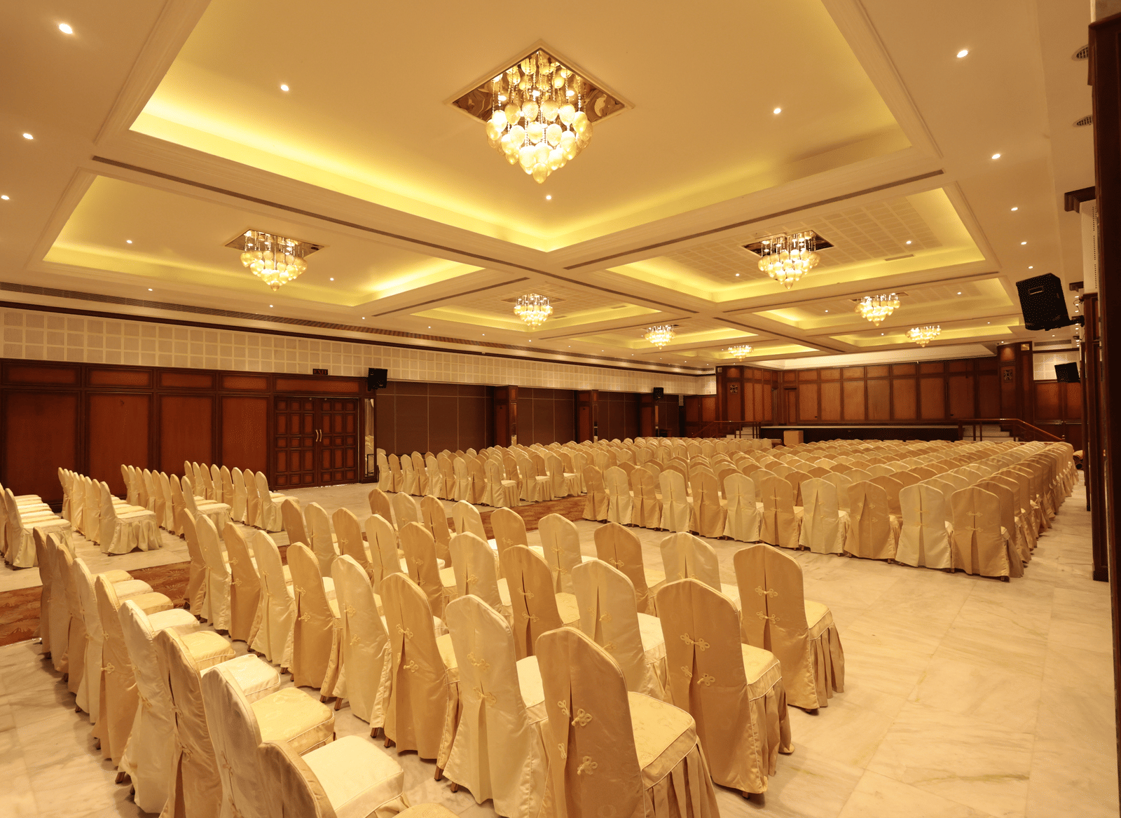 A diagonal view of the banquet hall from behind, with decorated chairs and yellow lighting | Cenneys Gateway