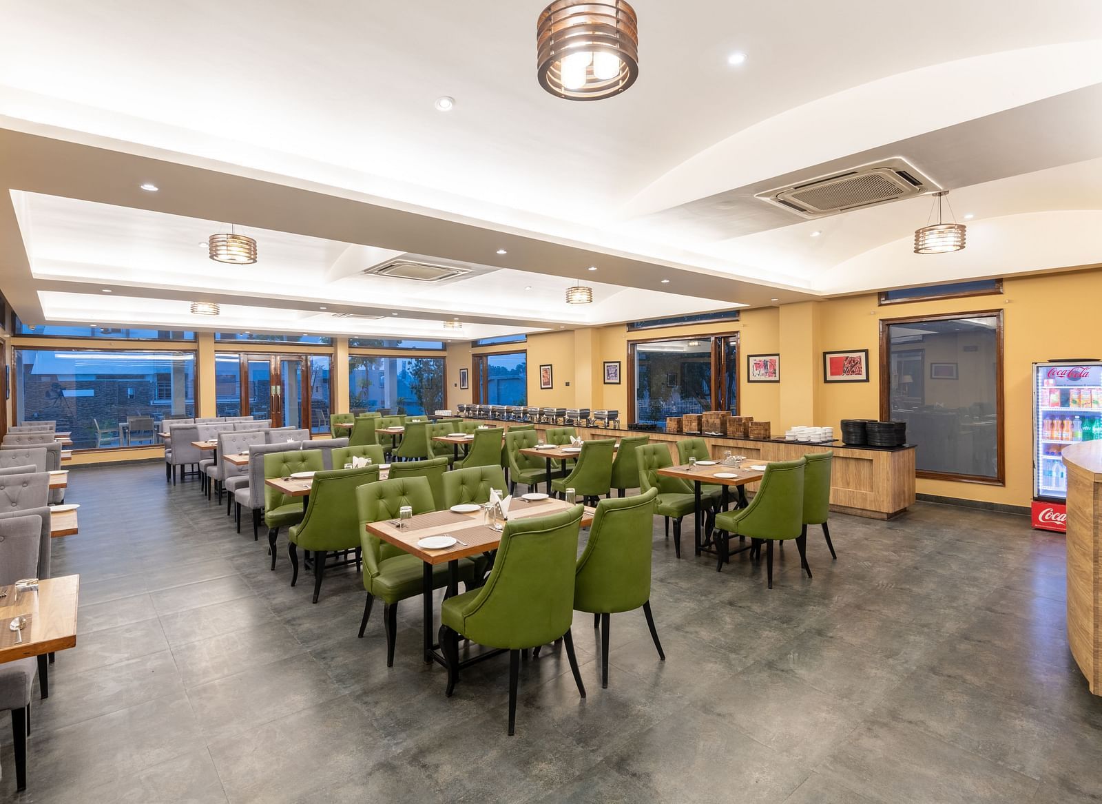 Brightly lit diagonal view of the restaurant at DLS Forest Vines Resort, showcasing tables and seating arranged for guests.