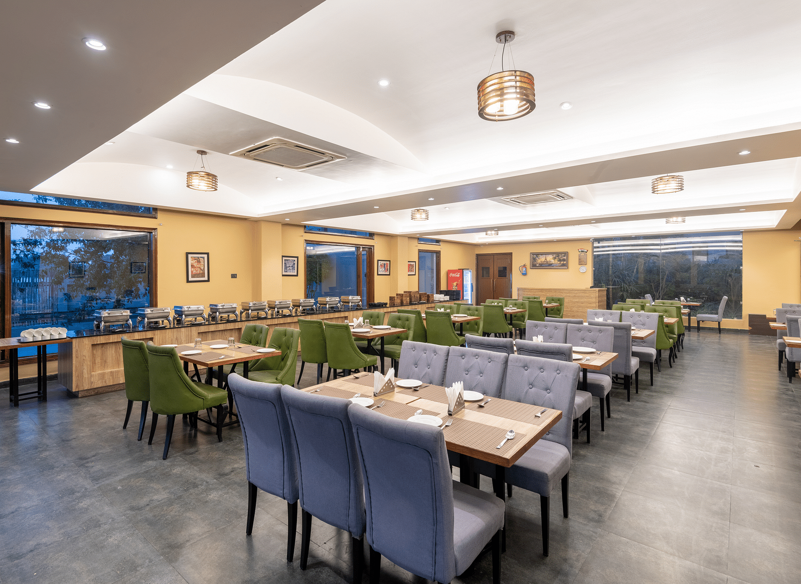 Diagonal view of the restaurant at DLS Forest Vines Resort, featuring tables and seating set for guests.